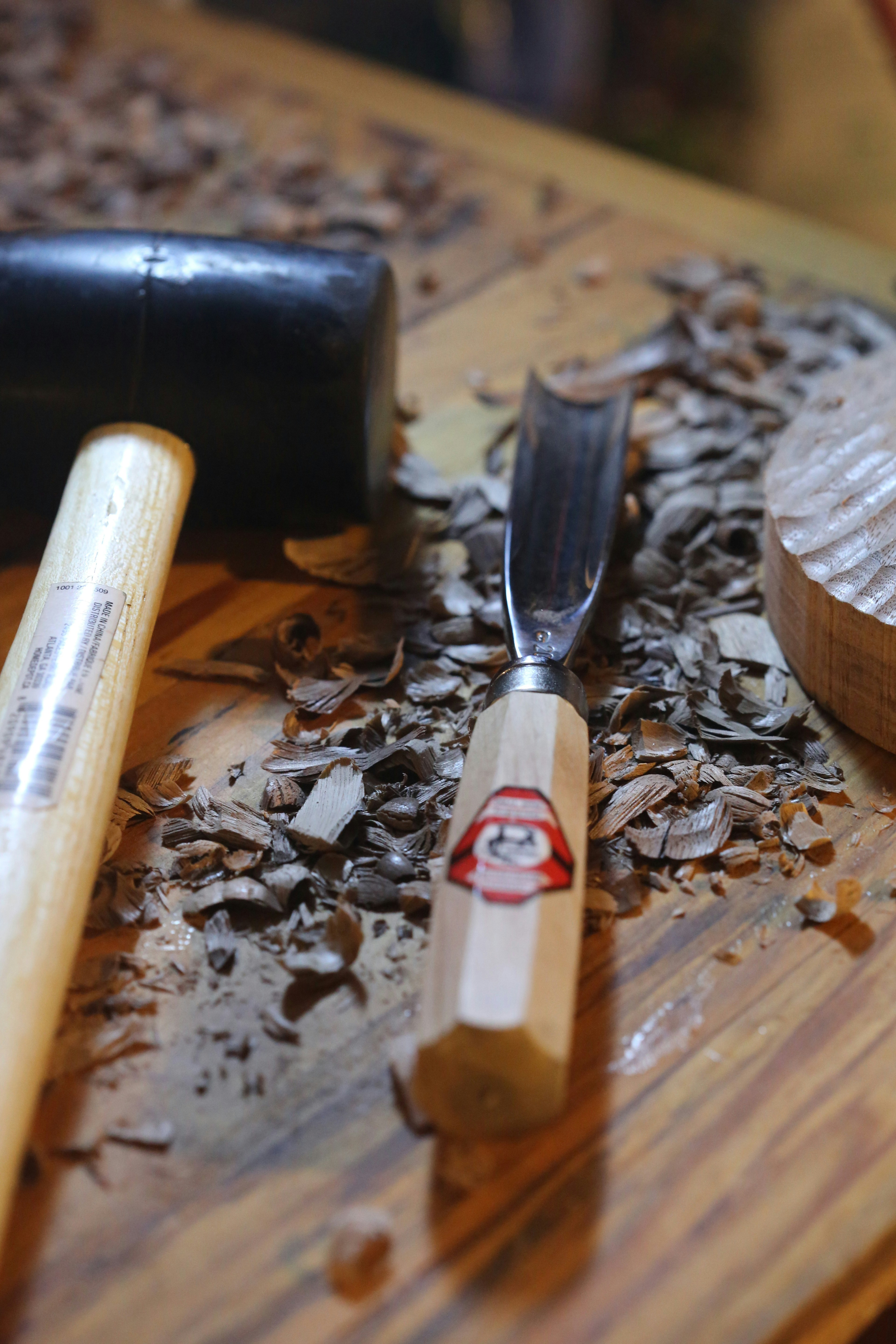 A craftsman's hands paring a dovetail joint in oak with a chisel by warm window light